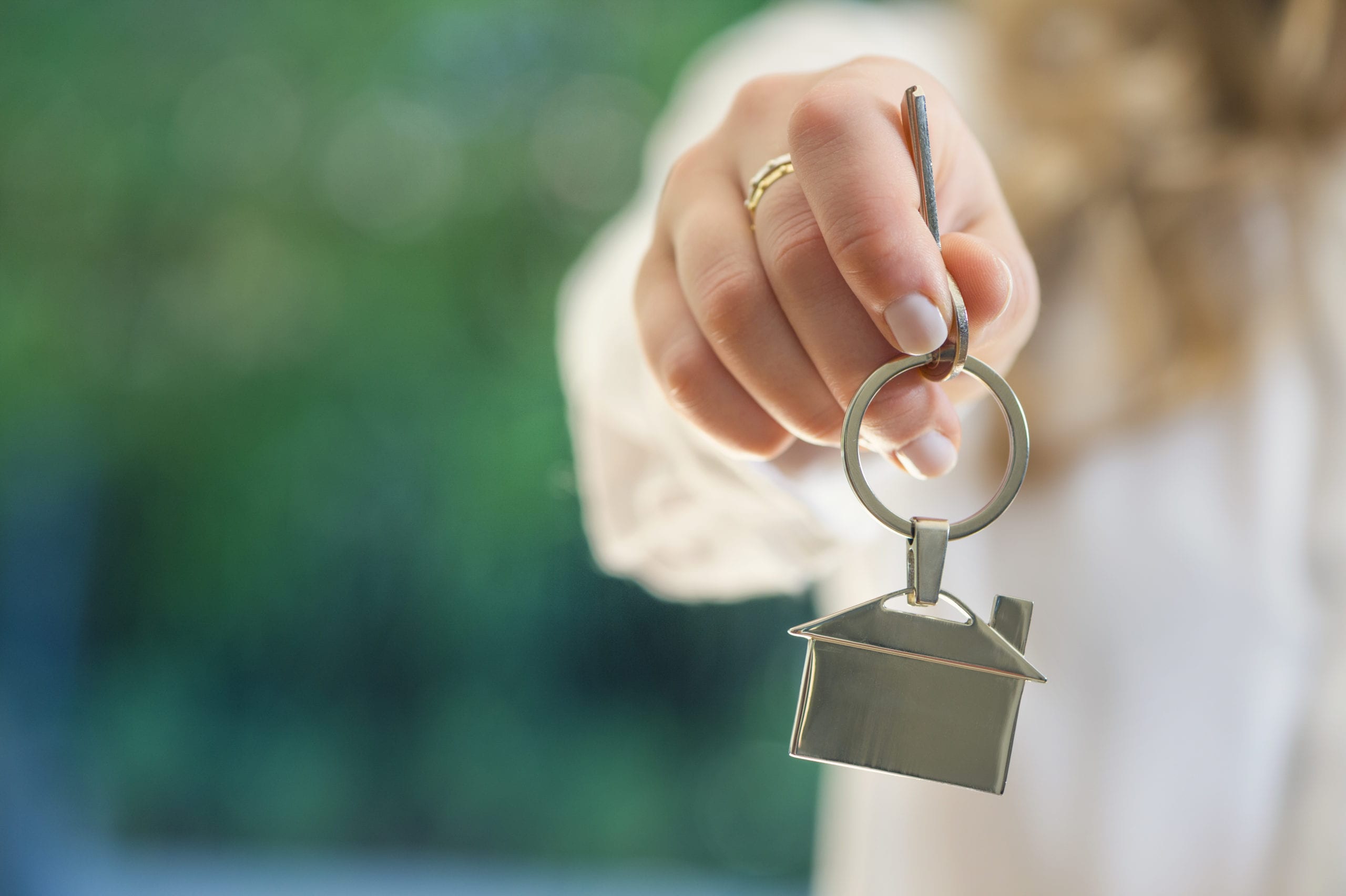 Real estate agent handing over the keys to a home. The key ring is house shaped. Copy space